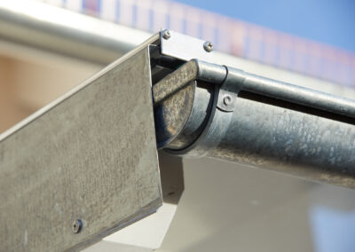 Detaillierte Ansicht eines verzinkten Regenrinnensystems mit Traufblech an einem weißen Holz-Terrassendach.