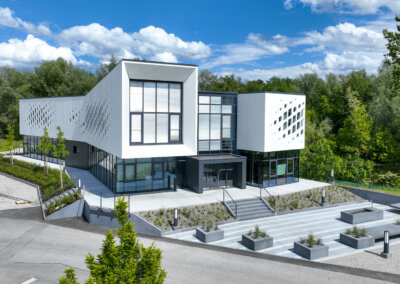 Luftbild eines modernen Bürogebäudes von Stangl AG Betonbau in Waldkraiburg mit einzigartiger Metallfassade und grüner Umgeb…