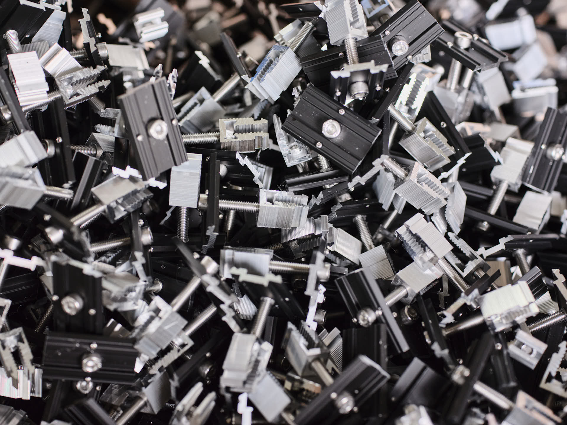 Photovoltaik Klemmen Alu schwarz eloxiert Detailaufnahme schwarzer und silberner Aluminium-Klemmen für Photovoltaikmodule, Schrauben und Halterungen für Solaranlagen