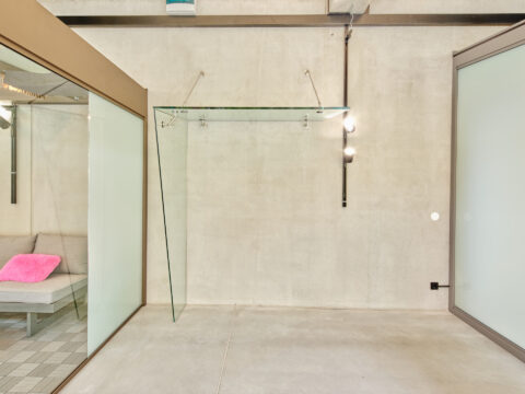 Abgehängte Glas-Eingangsüberdachung mit vertikalem Seitenelement in einer modernen Ausstellung, minimalistisches Design.