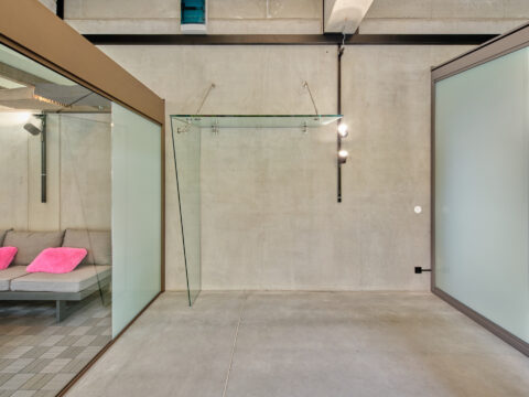 Moderne abgehängte Glasüberdachung in einer Ausstellungshalle, idealer Wetterschutz für Eingangsbereiche.