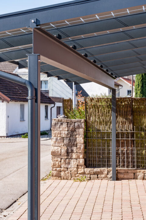 Detailansicht eines modernen anthrazit pulverbeschichteten Aluminium-Carports mit integrierten Photovoltaikmodulen für priva…