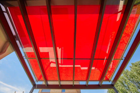 Rote Weinor Aufdachmarkise WGM Top OptiStretch auf Aluminium-Terrassenüberdachung in Landshut bietet optimalen Sonnenschutz.