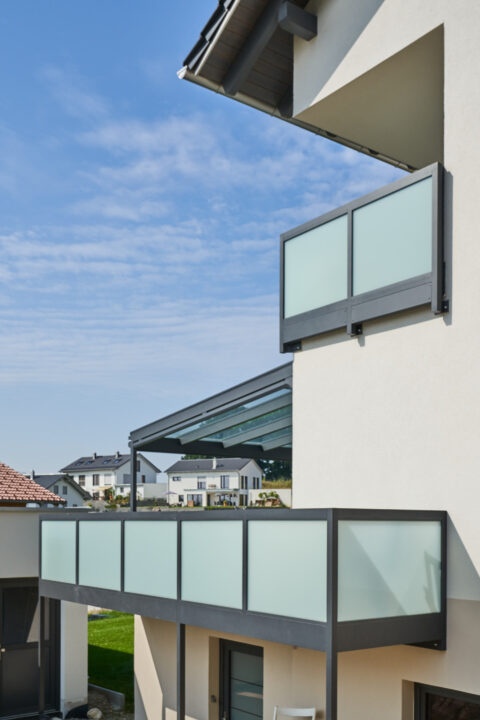 Moderne Balkonkonstruktion mit Mattglas-Brüstung und Glasüberdachung an einem Einfamilienhaus in Dorfen.