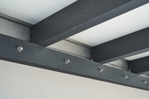 Detailansicht einer wasserdichten Balkonunterkonstruktion mit dunklen Metallträgern, befestigt an der Hausfassade.