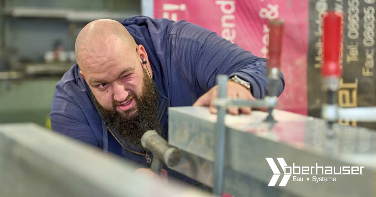 Handwerker bei Oberhauser Bau Systeme richtet Aluprofile präzise aus