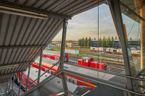 Blick von der modernen Glasbrücke am Bahnhof Mühldorf auf Gleisanlagen.