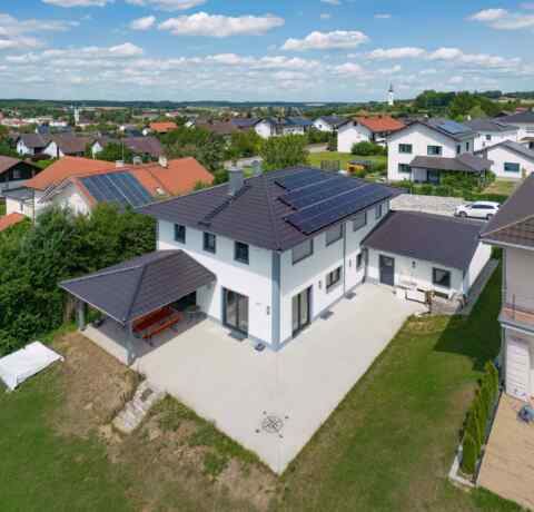Moderne Eigenheim-Photovoltaikanlage auf dem Dach eines weißen Hauses in Neumarkt St. Veit an einem sonnigen Tag.