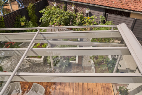 Aufdachmarkise Weinor WGM Top OptiStretch über Glasdach eines Wintergartens in Zorneding, mit darunterliegendem Garten.