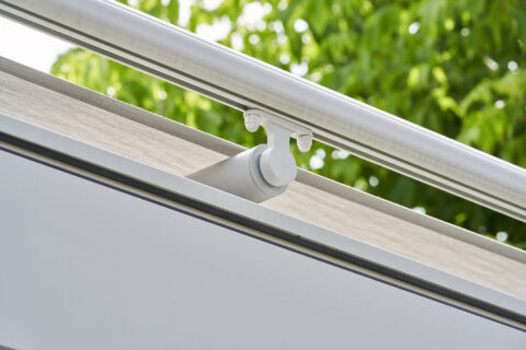 Detailaufnahme eines Distanzrohrs und der Montagemmechanik einer modernen Terrassenbeschattung unter Glaselementen.