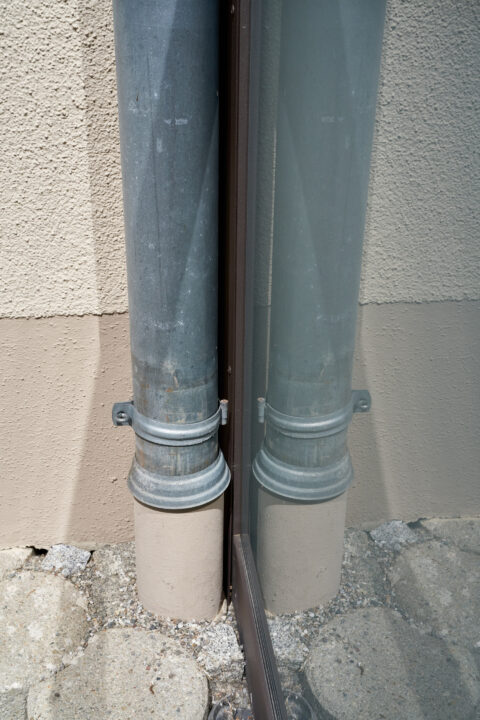 Detaillierte Ansicht eines Metall-Fallrohrs zur effektiven Entwässerung eines Photovoltaik-Terrassendachs in Niederbergkirch…