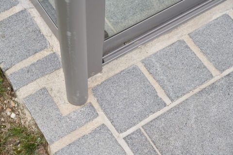 Detailaufnahme der Entwässerung eines Kaltwintergartens mit Terrassenüberdachung auf gepflastertem Untergrund in Kolbermoor.