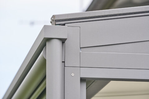 Detailaufnahme der Entwässerung einer modernen Aluminium Terrassenüberdachung mit integriertem Fallrohr und Regenrinne.