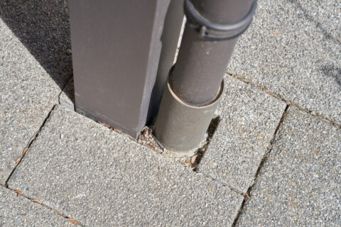 Detaillierte Ansicht des Fallrohranschlusses einer Terrassenüberdachung zur effizienten Wasserableitung auf gepflastertem Un…