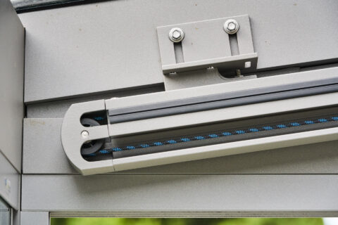 Detailaufnahme der Führungsschiene einer Weinor Sottezza OptiStretch Unterdachmarkise mit Spannseil und Befestigungselementen.