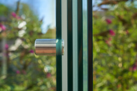 Close-up of a stainless steel handle on a Sunparadise VG 15 all-glass sliding system, providing weather protection for a con…