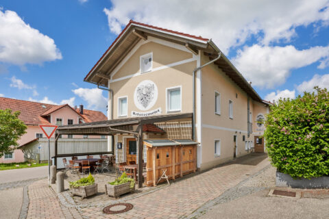 Schützenwirt Niederbergkirchen: Traditionelles bayerisches Gasthaus mit überdachtem Außenbereich und Tischen unter blauem Hi…
