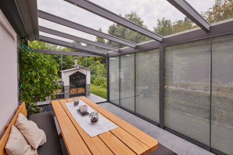 Gemütliche Terrasse mit geschlossener Glasüberdachung und Schiebewänden, ideal für alle Jahreszeiten.