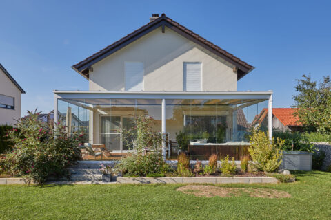Moderner Glasterrassen-Anbau an Einfamilienhaus in Oberpframmern als Kaltwintergarten für ganzjährigen Wind- und Wetterschut…