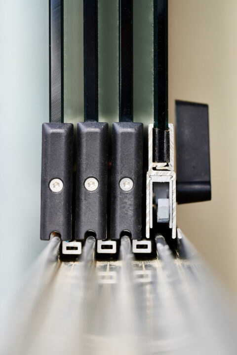 Detaillierter Blick auf das hochwertige Schienensystem von Glasschiebeelementen einer Terrassenüberdachung für optimalen Wet…