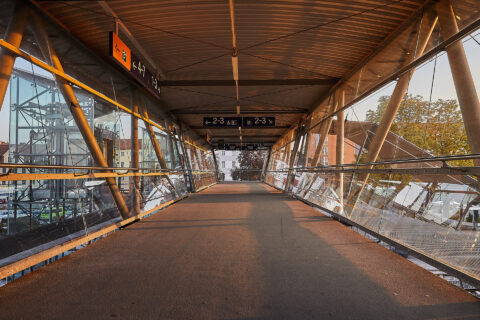 Moderner Glas-Stahl-Glastunnel über Bahngleisen zum Übergang zwischen den Bahnsteigen 2-3 und 4-7 am Bahnhof Mühldorf, mit A…