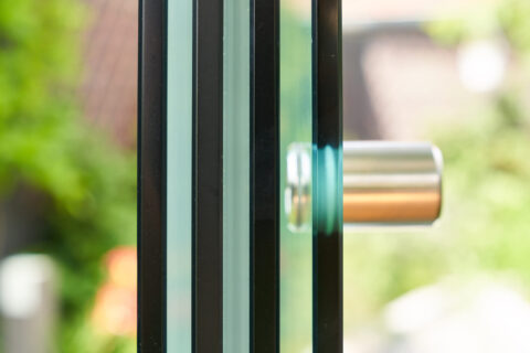 Detailansicht einer modernen Glaswand mit Mehrscheiben-Isolierglas und elegantem Edelstahlgriff für Wintergärten.