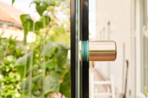 Detailaufnahme eines modernen Edelstahlgriffs an einer Sunparadise VG 15 Glasschiebeanlage, perfekt integriert in einen Wint…