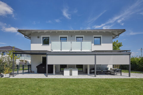 Modernes Einfamilienhaus mit stilvoller Terrassenüberdachung sowie integrierten Aufdach- und Seitenmarkisen.
