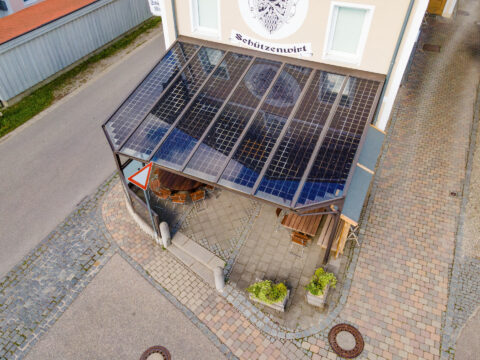 Individuelle Terrassenüberdachung mit integrierten PV-Modulen über dem Außenbereich des Schützenwirt in Niederbergkirchen.