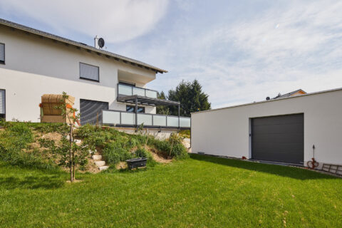 Individuelle Balkonüberdachung und Terrassenkonstruktion aus Aluminium an einem modernen Einfamilienhaus in Dorfen.