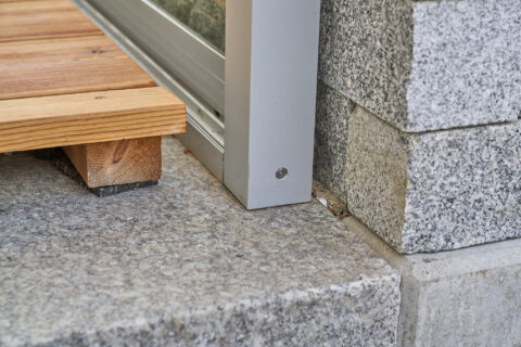 Detailansicht des Übergangs von Holzterrasse zu Wintergartenrahmen und Granitbelag in Zorneding.
