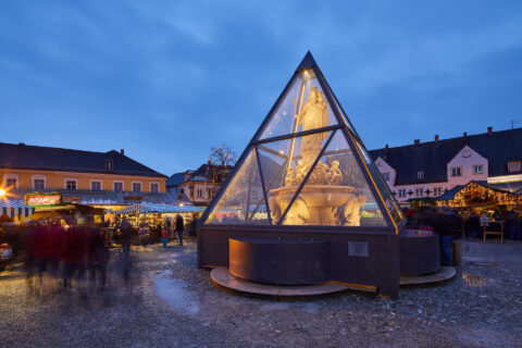 Glas-Einhausung um Marienbrunnen in Altötting: Optimal geschützt, zauberhaft beleuchtet am Christkindlmarkt.