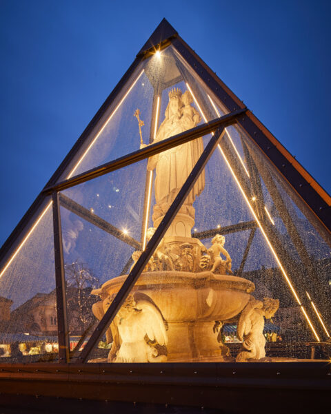 Beleuchtete Glaspyramide schützt den Marienbrunnen in Altötting vor Witterungseinflüssen im Winter.