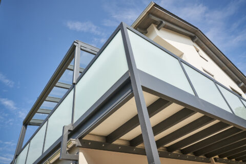 Maßgefertigte Balkonkonstruktion aus pulverbeschichtetem Aluminium mit Glasgeländer und transparenter Überdachung in Dorfen.