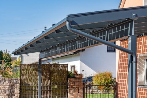 Anthrazitfarbener Photovoltaik Carport aus Aluminium mit integrierten Solarmodulen vor einem Wohnhaus in Mühldorf am Inn