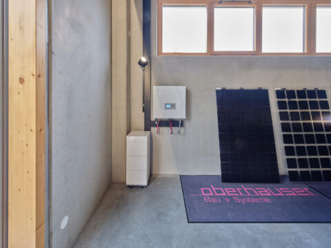 Photovoltaik Hybridwechselrichter und Batteriespeicher von Oberhauser Systeme mit Solarmodulen in unserer Ausstellung.