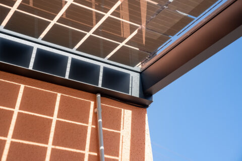 Detailansicht der professionellen Kabelführung eines Photovoltaik-Carports an einer Hauswand unter den Solarmodulen in Mühld…