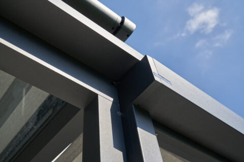 Ausschnitt eines modernen anthrazitfarbenen Terrassendachs mit integrierter Aufdachmarkise, Aluminiumkonstruktion.