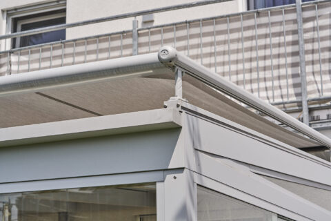 Nahaufnahme einer modernen, geschlossenen Terrassenüberdachung in RAL 9006, pulverbeschichtet, mit integrierter Sonnenmarkise
