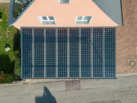 Luftbild eines modernen Photovoltaik-Carports mit Solarmodulen vor einem Wohnhaus in Mühldorf am Inn, optimiert für nachhalt…