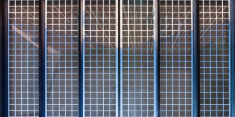 Detaillierte Ansicht vertikal angeordneter Glas-Photovoltaikmodule eines Carports, die Sonnenlicht reflektieren und Energie…