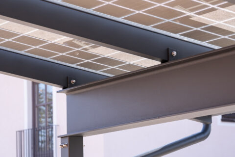 Detaillierte Ansicht der Sparrenkonstruktion eines PV Carports mit transparenten Solarmodulen, robusten Metallträgern und Ve…