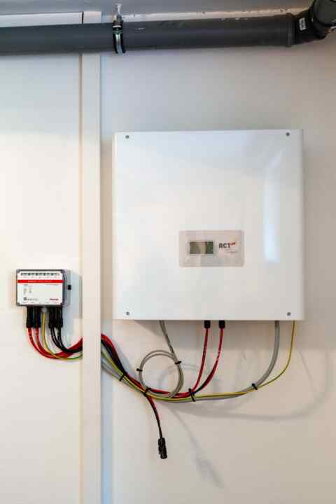 RCT Photovoltaik-Wechselrichter und SMA Monitoring-Einheit an Wand installiert, mit farbigen Kabelanschlüssen.