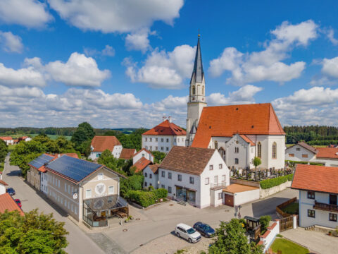 Luftaufnahme von Niederbergkirchen: Schützenwirt mit PV Terrassenüberdachung und Solaranlage auf dem Dach, im Hintergrund di…