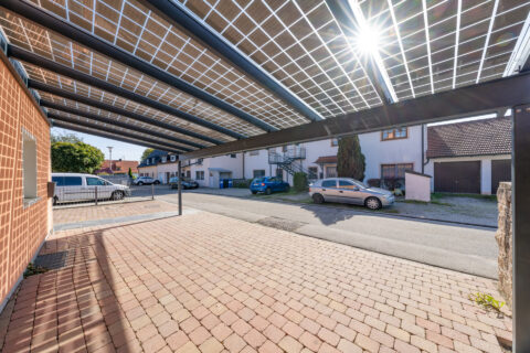 Modernes Solar-Carport mit integrierten Photovoltaikmodulen im Gegenlicht über einem privaten Stellplatz in Mühldorf.