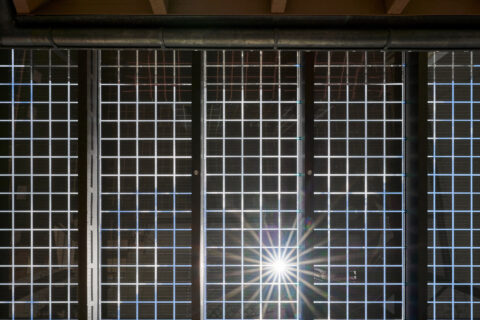 Von unten fotografierte Terrassenüberdachung aus transparenten Solarmodulen, durch die das Sonnenlicht fällt und eine Sternf…