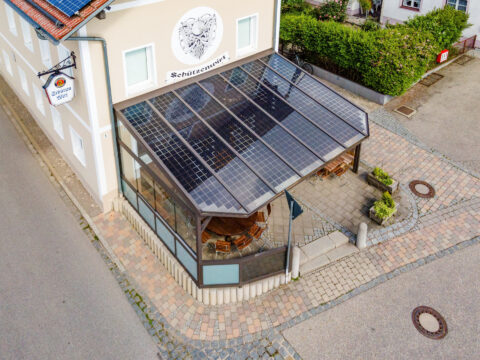 Luftaufnahme einer maßgefertigten Solarterrasse mit integrierten PV-Modulen an einer Aluminiumkonstruktion am Gasthof Schütz…