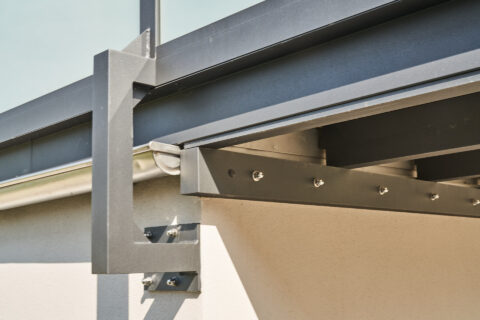 Detaillierte Ansicht spezieller dunkelgrauer Konsolen für Balkongeländer und Überdachung mit Entwässerungssystem.