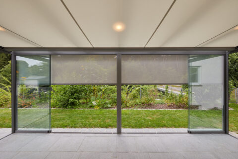 Modernes Terrassendach mit integriertem Unterdach-Sonnenschutz und Glas-Schiebeelementen, bietet Schatten und Komfort.