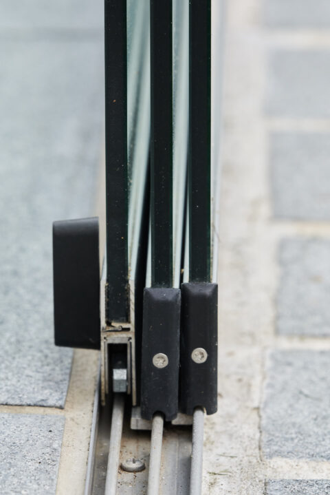 Detaillierte Ansicht der Bodenschiene und gestapelten Glaspaneele einer Sunparadise VG 15 Schiebeanlage für Kaltwintergärten.